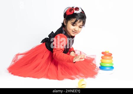 Fille indienne asiatique jouant avec des blocs de superposition avec des formes de tri isolées sur fond blanc. Amusement, activité, pré-école, éducation, maternelle, Banque D'Images