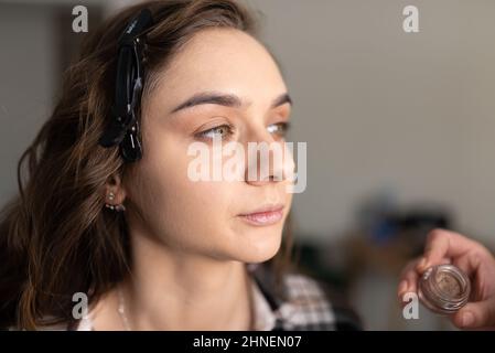 Maquilleuse application de l'ombre oculaire à la paupière inférieure d'une fille avec un pinceau. Photo de haute qualité Banque D'Images