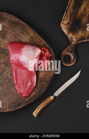 Vue de dessus du rouleau de chapeau de ribeye brut sur le bois sur la plaque de broyage Banque D'Images