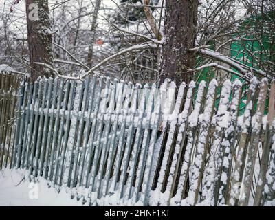 Vieille clôture en bois inclinée de la neige, scène d'hiver Banque D'Images