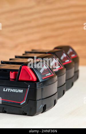 Batterie pour perceuse sans fil. Pile de tournevis. Quatre batteries avec indicateur de charge se trouvent sur un fond en bois Banque D'Images