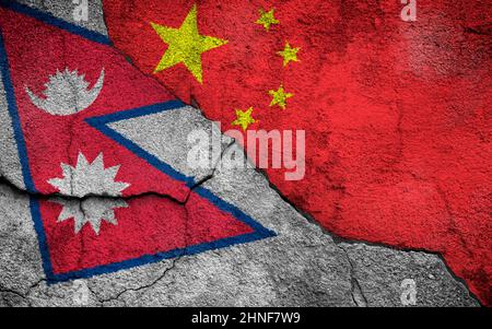 Photo plein cadre des drapeaux abîmés du Népal et de la Chine peints sur un mur fissuré. Banque D'Images