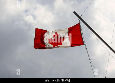 Angle bas du drapeau canadien suspendu sur des cordes sous un ciel nuageux Banque D'Images