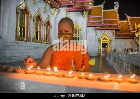 Bangkok, Thaïlande. 16th févr. 2022. Le moine bouddhiste thaïlandais allume des bougies avant de se promener dans le temple pour marquer le jour de Makha Bucha au Wat Benchamabophit Dusitvanaram, également connu sous le nom de Temple de marbre à Bangkok. Makha Bucha ou Magha Puja également connu comme le jour de l'Assemblée quadruple est l'un des jours les plus saints bouddhistes célébrés le jour où le Seigneur Bouddha a donné le premier sermon sur l'essence du bouddhisme dans ses disciples de moine ordonnés de 1 250 assemblés tous par spontanément rassemblés sans un rendez-vous. Crédit : SOPA Images Limited/Alamy Live News Banque D'Images