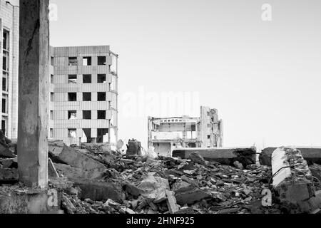 Le grand bâtiment en béton détruit avec un tas d'énormes fragments de pieux et de poutres. Arrière-plan. Photo en noir et blanc. Banque D'Images