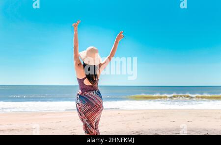 Femme avec chapeau de dos sur la plage, jeune femme levant les mains sur la plage. Rivas, Nicaragua Banque D'Images