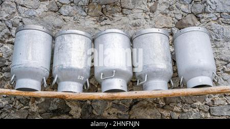 Canettes de lait alignées sur un banc en bois, façade en pierres rugueuses d'un alpage, Gralaialm, Alpenpark Karwendel, Tyrol, Autriche Banque D'Images