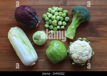 Différents types de chou sur une table en bois brun. Vue de dessus. Gros plan. Brocoli, choux de Bruxelles, chou-fleur, chou rouge, vert ca Banque D'Images