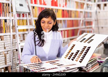 Femme choisissant la couleur de cheveux de la palette au magasin Banque D'Images