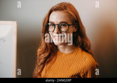 Portrait rapproché d'un enseignant portant des lunettes à cheveux rouges et un visage à l'état de taches avec un sourire éclatant. Portrait de gros plan tendance. Gros plan portrait. Entreprise Banque D'Images