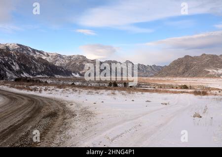 Une fourche dans les routes de champ dans la steppe enneigée d'une belle vallée entourée de montagnes d'hiver. Altaï, Sibérie, Russie. Banque D'Images