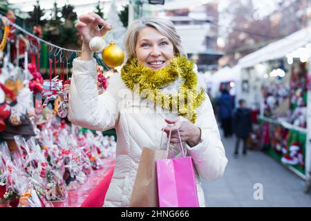 Bonne femme mûre en guirlande avec des jouets de Noël à la foire Banque D'Images