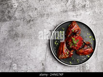 Ailes de poulet rôties avec risotto aux betteraves sur une assiette ronde sur fond gris foncé. Vue de dessus, plan d'appartement Banque D'Images