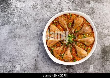 Pilons de poulet cuits au four et riz avec dans un plat blanc sur fond gris foncé. Vue de dessus, plan d'appartement Banque D'Images