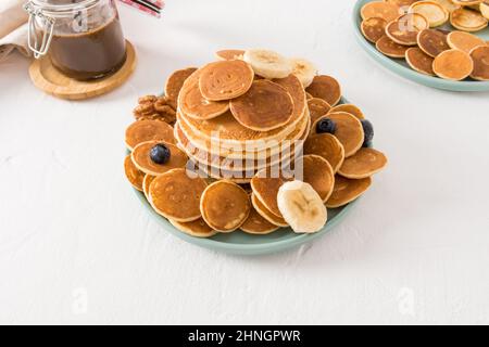 beaucoup de crêpes maison différentes sur une assiette avec des baies et des tranches de banane. pâte de chocolat pour compléter le goût sucré. fond blanc Banque D'Images