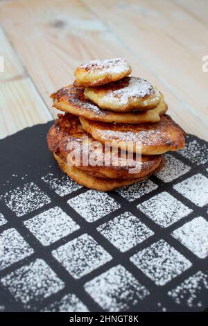 crêpes au fromage cottage (papanasi roumain) sur une tuile de pierre noire avec poudre de sucre saupoudrée Banque D'Images
