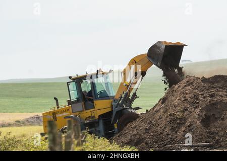 Chargeur frontal ou chargeur sur roues qui récolte de la terre ou du sable sur une pile dans une ferme en milieu rural dans le Cap occidental, en Afrique du Sud Banque D'Images