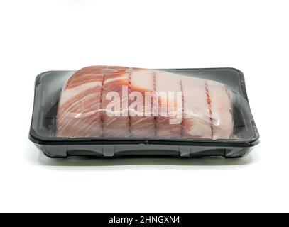 Gros plan de la coupe brute de filet de porc, attaché et roulé avec la ficelle de boucher dans un contenant en plastique noir, enveloppé de film plastique de conservation pour la vente sur Banque D'Images