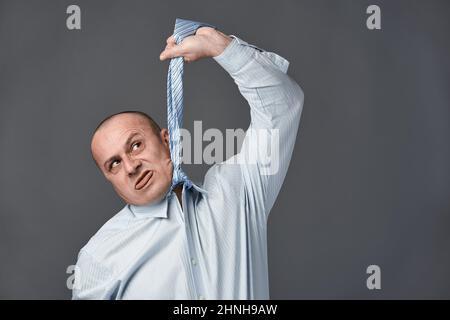 Homme d'affaires frustré imitant de se raccrocher avec son cravate Banque D'Images