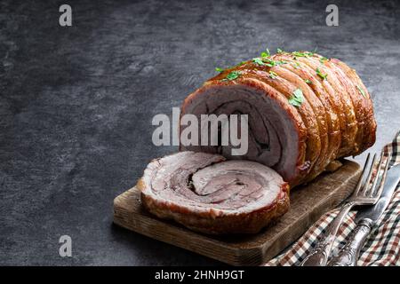 Roulé de viande de porc rôti en tranches avec herbes et épices sur fond de pierre grise Banque D'Images