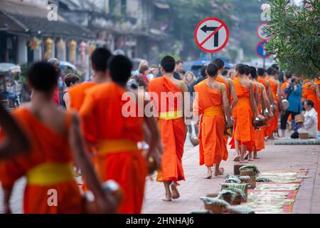 Les touristes prennent des photos de moines bouddhistes avec des cérémonies de remise d'alms bouddhistes dans la rue le matin. Luang Prabang, Laos. Banque D'Images