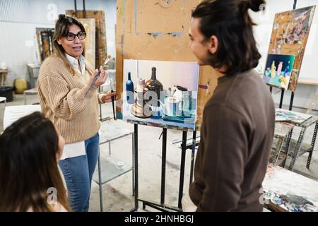 Professeur mature travaillant avec des étudiants en art pendant la classe de peinture à l'école - Focus sur le visage de femme Banque D'Images