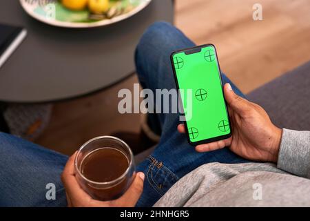 Gros plan d'un homme tenant un téléphone portable et une tasse de café Banque D'Images