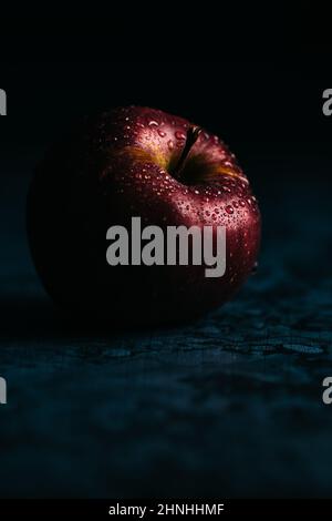 Pomme Dabinet rouge frais avec des gouttelettes d'eau dans la scène sombre et sinistre. Lumière spectaculaire Banque D'Images