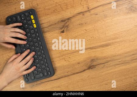 Mains féminines et clavier sans fil sur fond en bois. Concept d'espace de travail, travail à la maison, ordinateur et freelance, conception. Flat lay, vue de dessus Banque D'Images