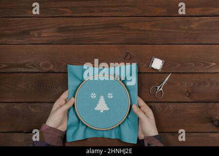 Broderie dans les mains des femmes, à plat. L'artisan présente un motif dans un cadre à broderie ronde, vue du dessus. Banque D'Images