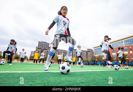 HAI'AN, CHINE - 17 FÉVRIER 2022 - les enfants d'un club de football pour filles dans une école primaire pratiquent les compétences de base pendant les heures de service après l'école à Ha Banque D'Images