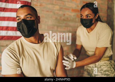 Soldat recevant un rappel du vaccin Covid-19 d'un médecin de l'armée. Un militaire des États-Unis se fait vacciner contre la coronavirus dans Banque D'Images