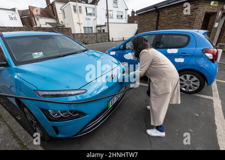 Femme d'âge moyen utilisant le point de charge de véhicule 'GeniePoint EV Charging' dans Hampshire , Angleterre, Royaume-Uni Banque D'Images