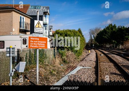 Des panneaux d'avertissement sur un passage à niveau informant le public qu'il doit se méfier des trains et que l'intrusion sur les voies ferrées entraînera des poursuites et une amende à p Banque D'Images