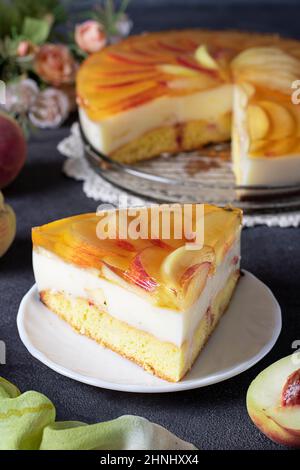 Gâteau de gelée maison avec pêches, crème et biscuit dans une assiette sur fond gris foncé Banque D'Images