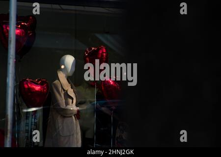 Ballons à cœur rouge sur une fenêtre du magasin pour célébrer la Saint-Valentin avec un mannequin. Un jour romantique d'amour. Photo de haute qualité Banque D'Images