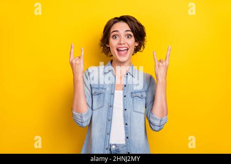 Photo de la jeune femme imprudente excitée montre le symbole de métal dur puildish isolé sur fond jaune Banque D'Images