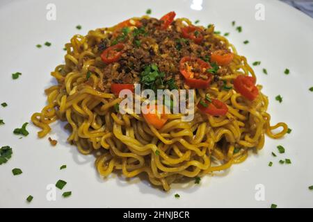 Savoureuses nouilles frites (mie goreng) avec des tranches de piment et des oignons frits. Servies sur une assiette blanche. Vue de dessus détaillée Banque D'Images