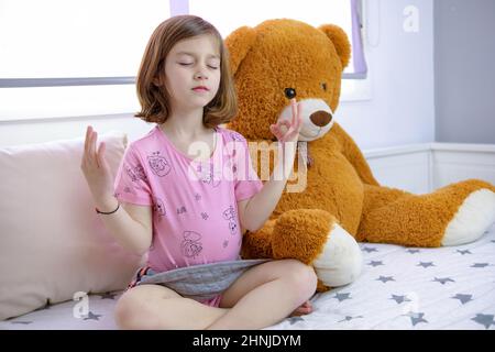 Belle fille européenne pratiquant et relaxant avec Mindfulness à côté de son animal en peluche à la maison Banque D'Images
