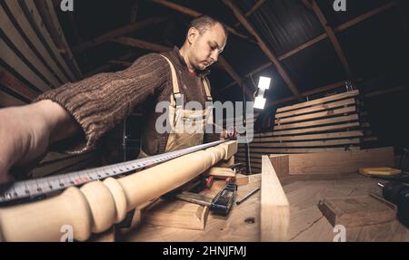 Un homme fabrique des produits en bois à l'aide d'outils spéciaux. Portrait d'un jeune menuisier au travail. Emploi dans l'industrie du bois Banque D'Images