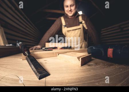Un homme fabrique des produits en bois à l'aide d'outils spéciaux. Portrait d'un jeune menuisier au travail. Emploi dans l'industrie du bois Banque D'Images