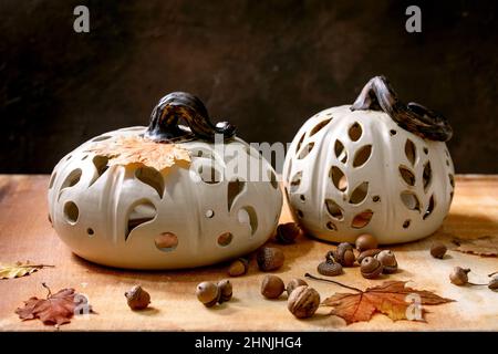 Décorations d'Halloween, ensemble de citrouilles blanches en céramique sculptées à la main, debout sur une table en pierre orange avec des feuilles d'automne et des glands. Holida d'Halloween Banque D'Images