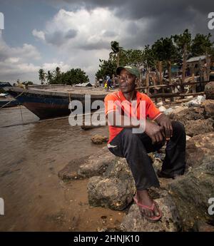 C'est Machamo c'est un pêcheur qui a vécu 35 ans dans un petit village de pêcheurs Kunduchi, près de Dar es-salaam en Tanzanie. Au cours des 7 dernières années, la mer montante a mangé loin à la plage avançant 35 mètres et est maintenant à quelques mètres de sa maison et du village. Dans une tentative désespérée de protéger son village, il a construit une défense contre les vagues en utilisant du bois de grève et des sacs pleins de déchets en plastique qui se lave sur les rives. Il sait que cela ne va pas vaincre la montée des vois, mais lui et sa famille n'ont pas d'autre endroit où aller. Banque D'Images