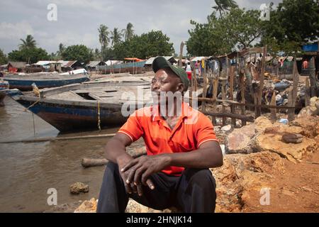 C'est Machamo c'est un pêcheur qui a vécu 35 ans dans un petit village de pêcheurs Kunduchi, près de Dar es salaam, en Tanzanie. Au cours des 7 dernières années, la mer montante a mangé loin à la plage avançant 35 mètres et est maintenant à quelques mètres de sa maison et du village. Dans une tentative désespérée de protéger son village, il a construit une défense contre les vagues en utilisant du bois de grève et des sacs pleins de déchets en plastique qui se lave sur les rives. Il sait que cela ne va pas vaincre la montée des vois, mais lui et sa famille n'ont pas d'autre endroit où aller. Banque D'Images