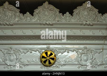 Détail du bord supérieur d'un poêle en faïence de style baroque-classique avec régulateur de ventilation. Banque D'Images