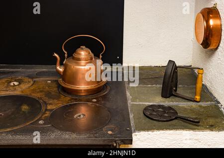 Des ustensiles de cuisine et de ménage anciens, certains en cuivre, ont été placés pour la décoration sur une cuisinière traditionnelle avec bois ou charbon. Banque D'Images