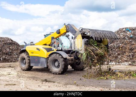 Bulldozer déplacement des déchets organiques à l'usine de recyclage du compost. Terrassement travaillant sur un tas de compost dans une installation industrielle Banque D'Images