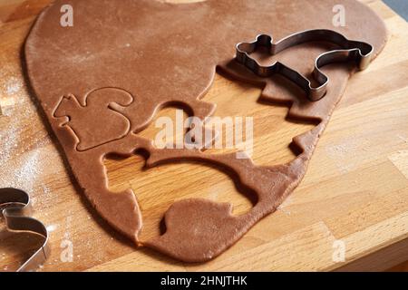 En coupant différentes formes de pâte à pain d'épice pour préparer des biscuits de Noël faits maison Banque D'Images