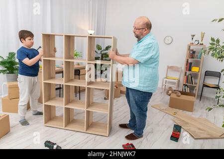 Un fils et son père déplacent une bibliothèque pliée dans un bol prévu. Banque D'Images