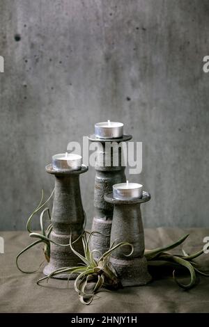 Trois différentes tailles artisanales bougies en céramique holdersavec la composition de la plante tillandsia air sur la toile de table vert foncé. Décoration intérieure, plantes vertes, u Banque D'Images